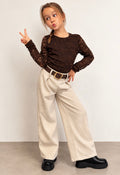 Meisje draagt een bruine kanten top met bloemenpatroon en lange mouwen, gecombineerd met een beige wide-leg pantalon.